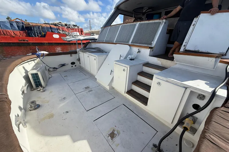  Yacht Photos Pics 1990 Denison Pilothouse Cockpit Motoryacht deck with storage compartments and steps, docked by a red ship.