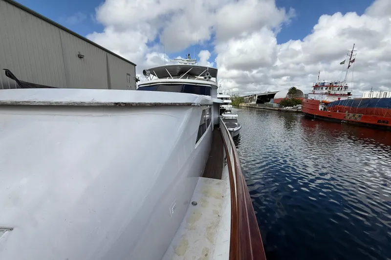  Yacht Photos Pics 1990 Denison Pilothouse Cockpit Motoryacht docked by a waterfront building under cloudy skies.