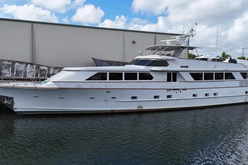  Yacht Photos Pics 1990 Denison Pilothouse Cockpit Motoryacht docked by a warehouse under a cloudy sky.