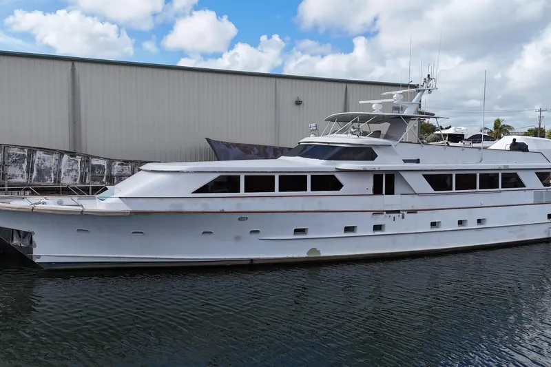  Yacht Photos Pics 1990 Denison Pilothouse Cockpit Motoryacht docked by a warehouse under a cloudy sky.