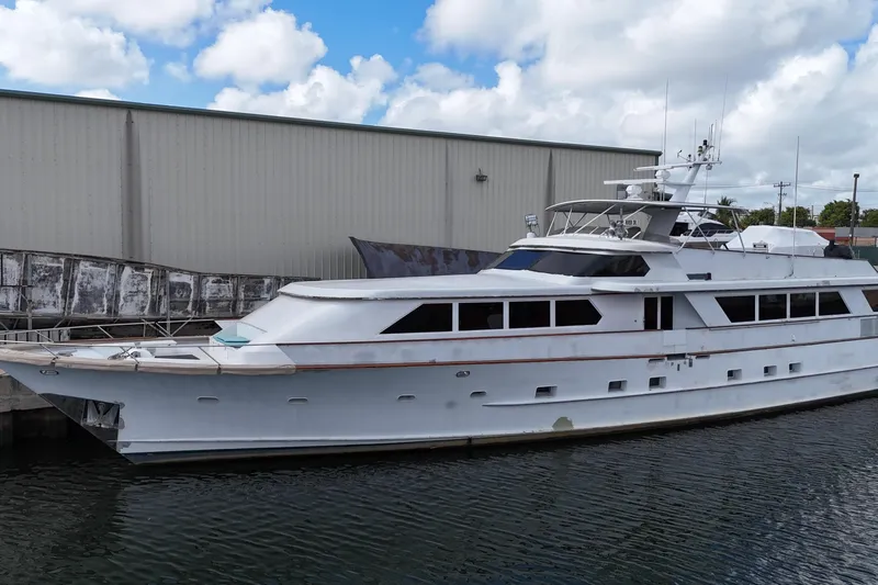  Yacht Photos Pics 1990 Denison Pilothouse Cockpit Motoryacht docked by a warehouse under a cloudy sky.