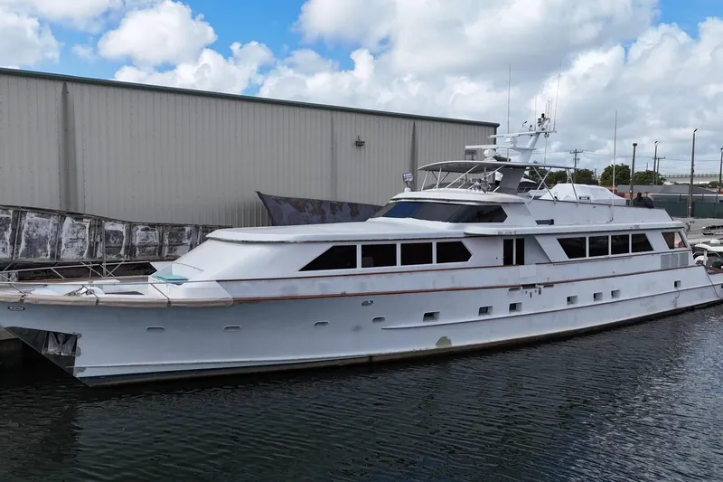  Yacht Photos Pics 1990 Denison Pilothouse Cockpit Motoryacht docked by industrial building under cloudy sky.