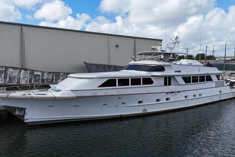  Yacht Photos Pics 1990 Denison Pilothouse Cockpit Motoryacht docked by a warehouse under cloudy skies.