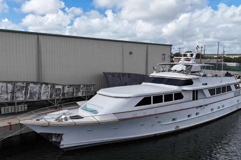  Yacht Photos Pics 1990 Denison Pilothouse Cockpit Motoryacht docked beside industrial building under cloudy sky.