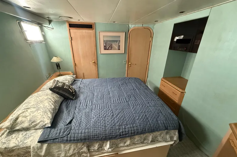  Yacht Photos Pics Cozy bedroom in 1990 Denison Pilothouse Cockpit Motoryacht with blue bedding and wooden accents.