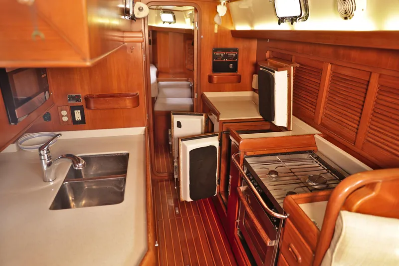 Oleta Yacht Photos Pics 2005 Tayana 48 yacht interior with wooden cabinetry, kitchen appliances, and cozy seating area.