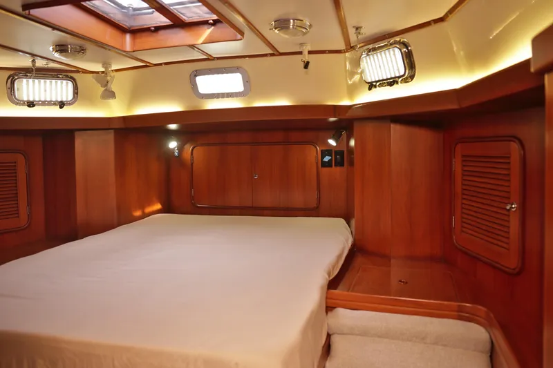 Oleta Yacht Photos Pics Luxurious wooden cabin interior of 2005 Tayana 48 yacht with cozy bed and ambient lighting.