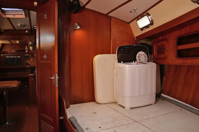 Oleta Yacht Photos Pics Interior of 2005 Tayana 48 yacht with wooden paneling and compact washing machine.