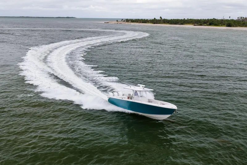  Yacht Photos Pics 2022 Jupiter 38 HFS boat cruising on open water near a lush coastline.