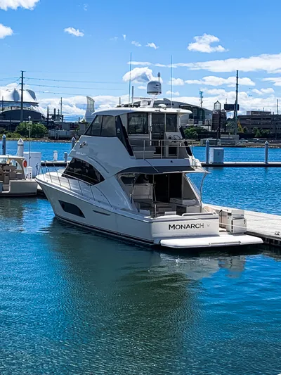  Yacht Photos Pics 2023 Riviera 57 Enclosed Flybridge yacht docked in a marina under a clear blue sky.