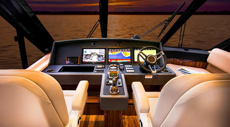  Yacht Photos Pics 2023 Riviera 57 Enclosed Flybridge helm with advanced navigation systems at sunset.