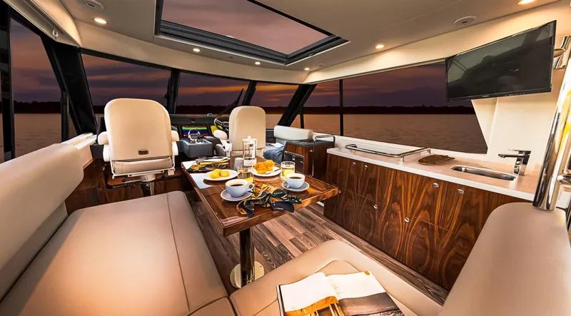  Yacht Photos Pics Luxurious interior of 2023 Riviera 57 Enclosed Flybridge yacht with dining setup at sunset.