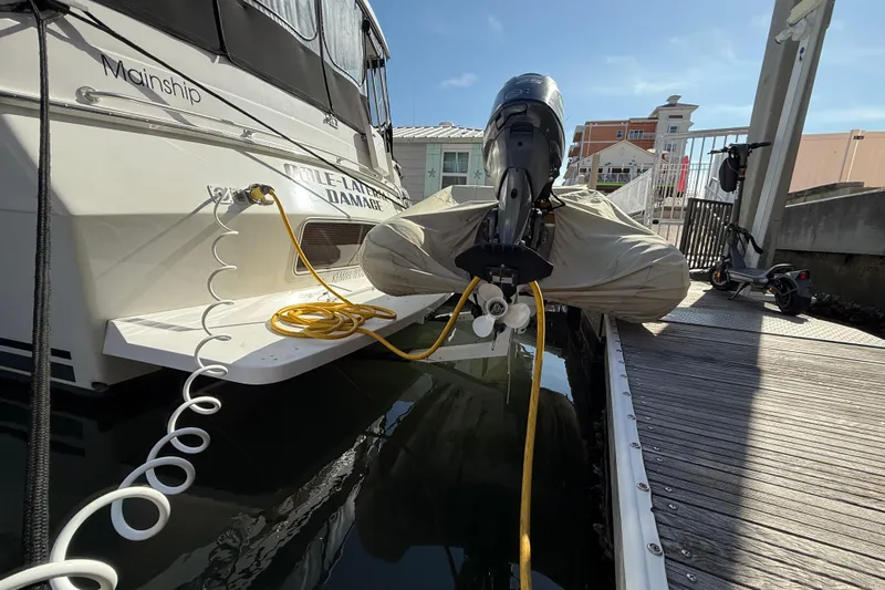 Cole-lateral Damage Yacht Photos Pics 1998 Mainship 47 Motor Yacht docked, with cables and covered outboard motor.