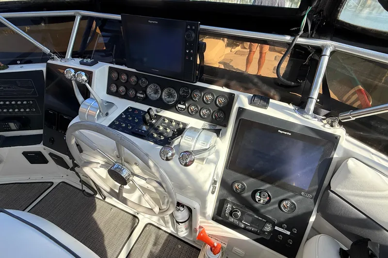 Cole-lateral Damage Yacht Photos Pics 1998 Mainship 47 Motor Yacht helm with steering wheel, gauges, and navigation screens.