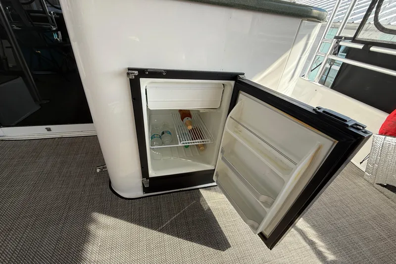 Cole-lateral Damage Yacht Photos Pics Open mini fridge on 1998 Mainship 47 Motor Yacht, containing water bottles and a wine bottle.