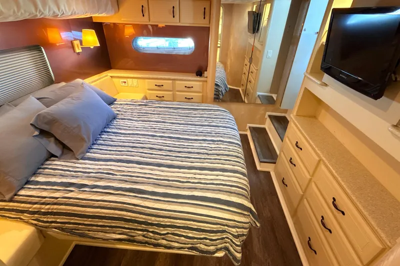 Cole-lateral Damage Yacht Photos Pics Luxurious bedroom interior of 1998 Mainship 47 Motor Yacht with striped bedding and ample storage.