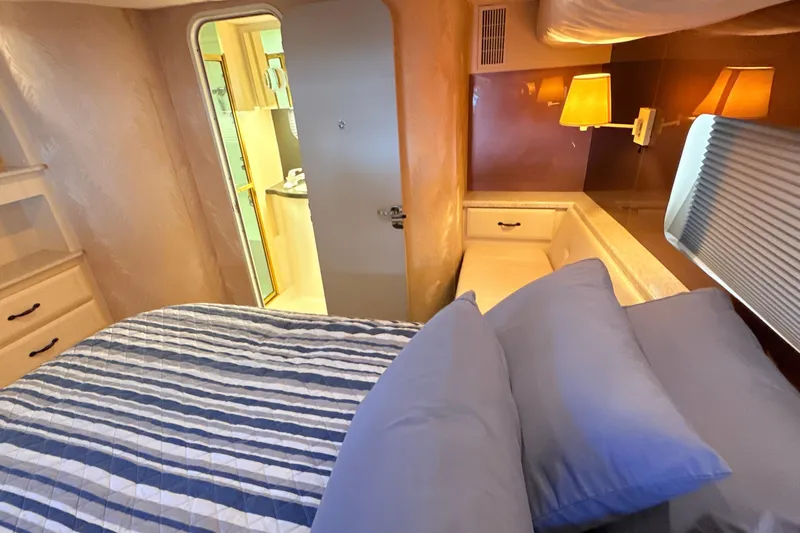 Cole-lateral Damage Yacht Photos Pics 1998 Mainship 47 Motor Yacht bedroom with striped bedding and warm lighting.