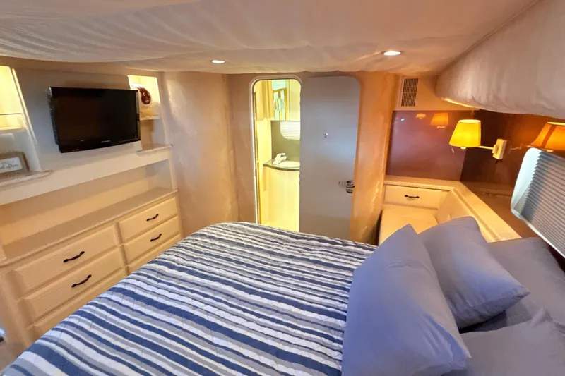 Cole-lateral Damage Yacht Photos Pics Cozy bedroom in 1998 Mainship 47 Motor Yacht with striped bedding and TV.