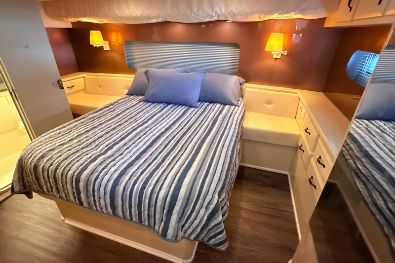 Cole-lateral Damage Yacht Photos Pics Cozy bedroom in 1998 Mainship 47 Motor Yacht with striped bedding and warm lighting.