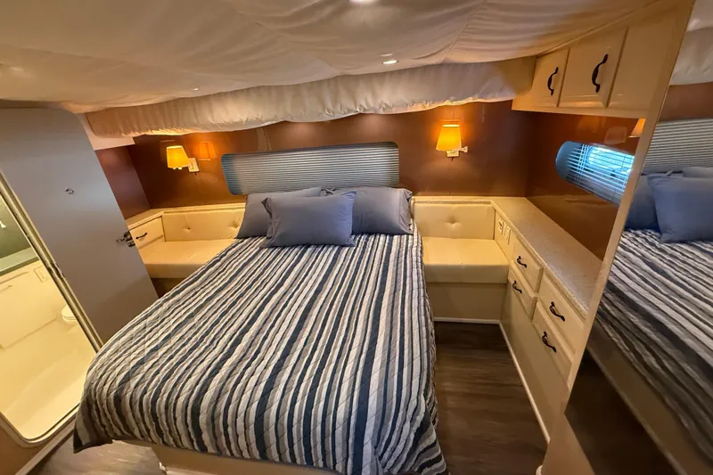 Cole-lateral Damage Yacht Photos Pics Cozy bedroom in 1998 Mainship 47 Motor Yacht with striped bedding and warm lighting.