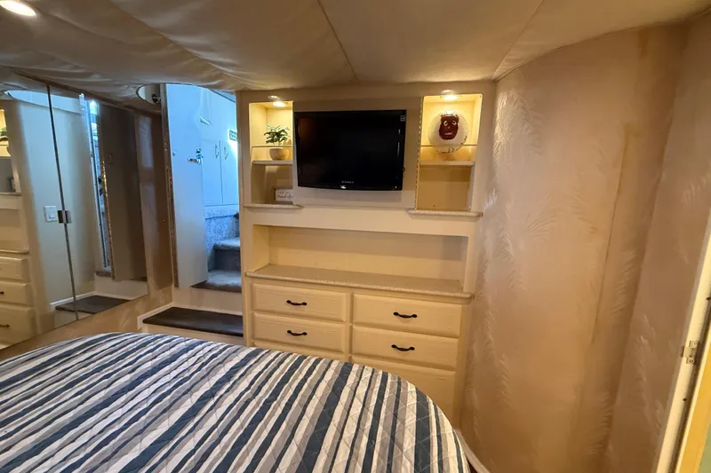 Cole-lateral Damage Yacht Photos Pics Cozy bedroom in 1998 Mainship 47 Motor Yacht with TV, drawers, and striped bedding.