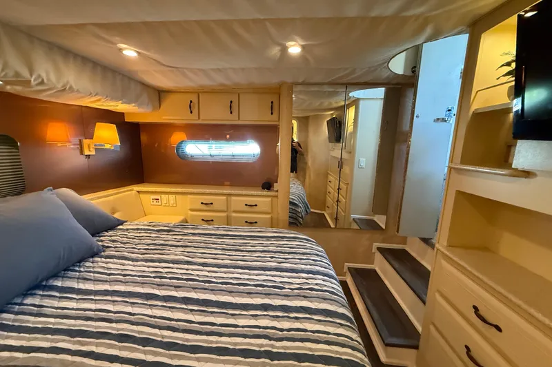Cole-lateral Damage Yacht Photos Pics Cozy bedroom in 1998 Mainship 47 Motor Yacht with striped bedding and warm lighting.