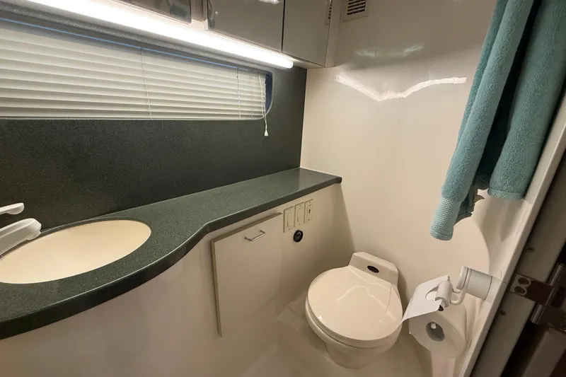 Cole-lateral Damage Yacht Photos Pics Bathroom interior of 1998 Mainship 47 Motor Yacht with sink, toilet, and teal towel.