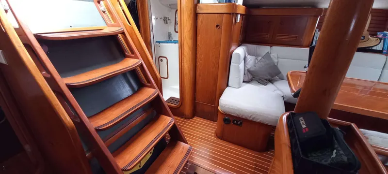 Roxanne Yacht Photos Pics Interior of 1990 Beneteau Oceanis Clipper 500 yacht, featuring wooden stairs and cozy seating area.