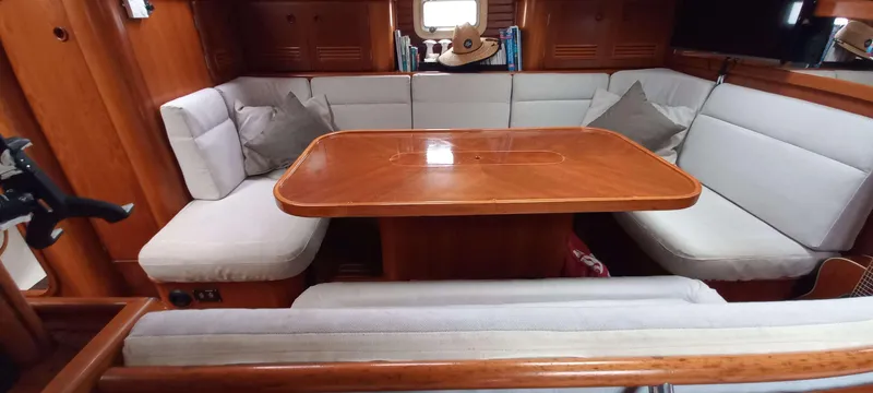 Roxanne Yacht Photos Pics Interior of 1990 Beneteau Oceanis Clipper 500 yacht with wooden table and cushioned seating.