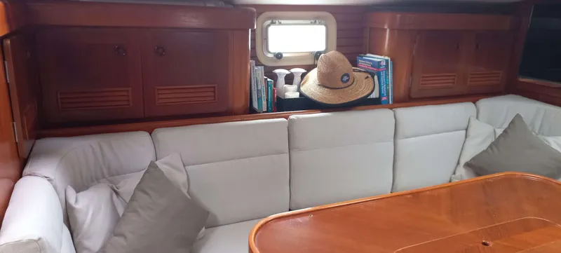 Roxanne Yacht Photos Pics Cozy interior of 1990 Beneteau Oceanis Clipper 500 with cushioned seating and wooden table.