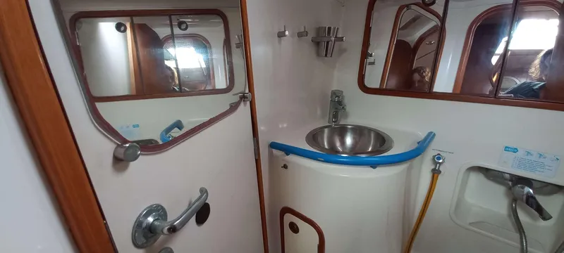 Roxanne Yacht Photos Pics Bathroom interior of 1990 Beneteau Oceanis Clipper 500 yacht, featuring sink and mirrors.