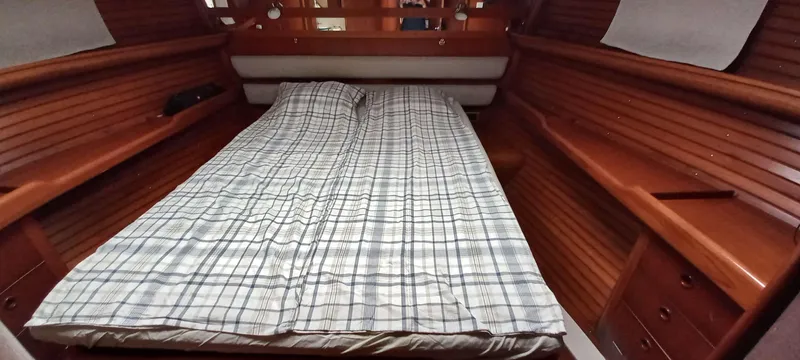 Roxanne Yacht Photos Pics Cozy cabin interior of 1990 Beneteau Oceanis Clipper 500 with wooden finish and plaid bedding.