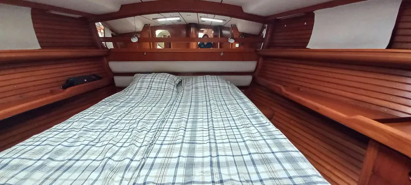 Roxanne Yacht Photos Pics Cozy cabin interior of 1990 Beneteau Oceanis Clipper 500 with wooden paneling and plaid bedding.