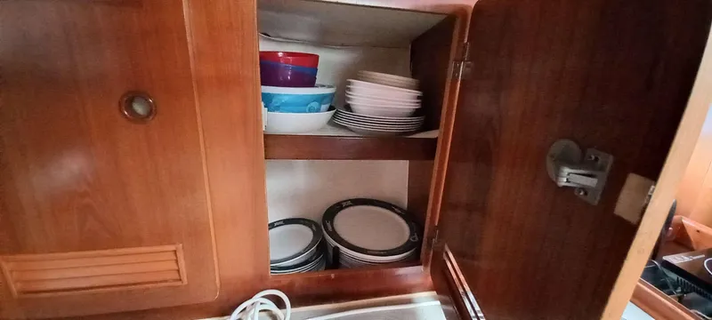 Roxanne Yacht Photos Pics Cabinet with dishes inside a 1990 Beneteau Oceanis Clipper 500 yacht kitchen.