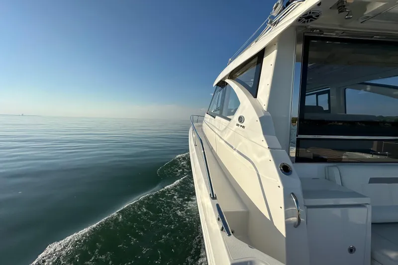  Yacht Photos Pics 2024 Pursuit OS 445 Offshore yacht cruising on calm waters under clear blue sky.