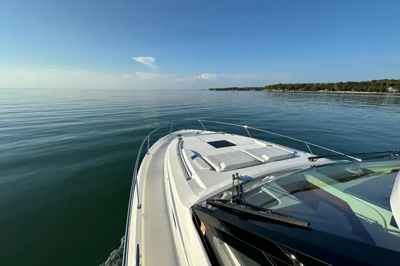  Yacht Photos Pics 2024 Pursuit OS 445 Offshore cruising on calm waters near a scenic coastline.