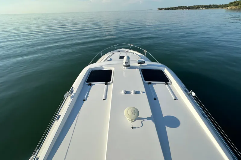  Yacht Photos Pics 2024 Pursuit OS 445 Offshore boat cruising on calm waters, top deck view.