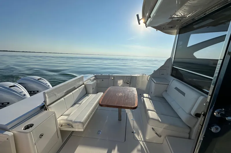  Yacht Photos Pics 2024 Pursuit OS 445 Offshore boat interior with seating and table, cruising on calm waters.