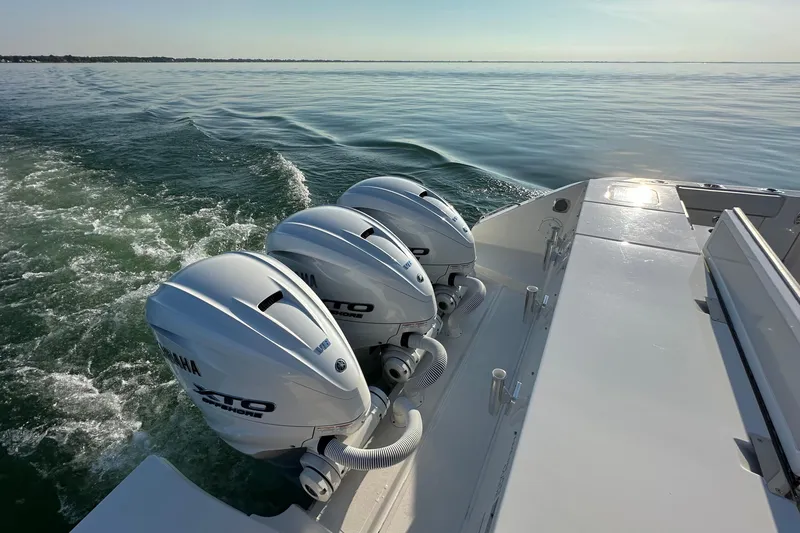  Yacht Photos Pics 2024 Pursuit OS 445 Offshore boat with triple Yamaha engines cruising on calm water.