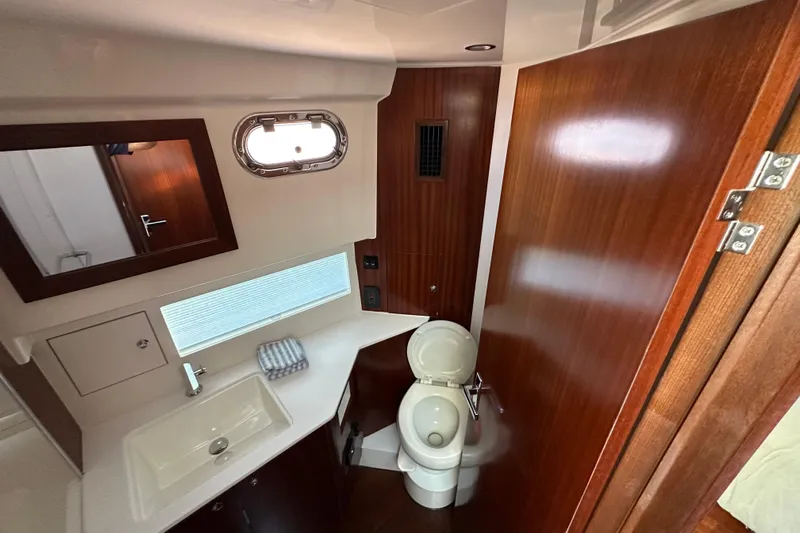  Yacht Photos Pics 2024 Pursuit OS 445 Offshore yacht bathroom with sink, toilet, and wooden cabinetry.
