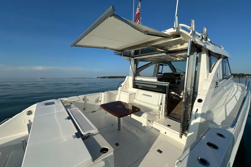  Yacht Photos Pics 2024 Pursuit OS 445 Offshore yacht with open deck and seating area on calm water.