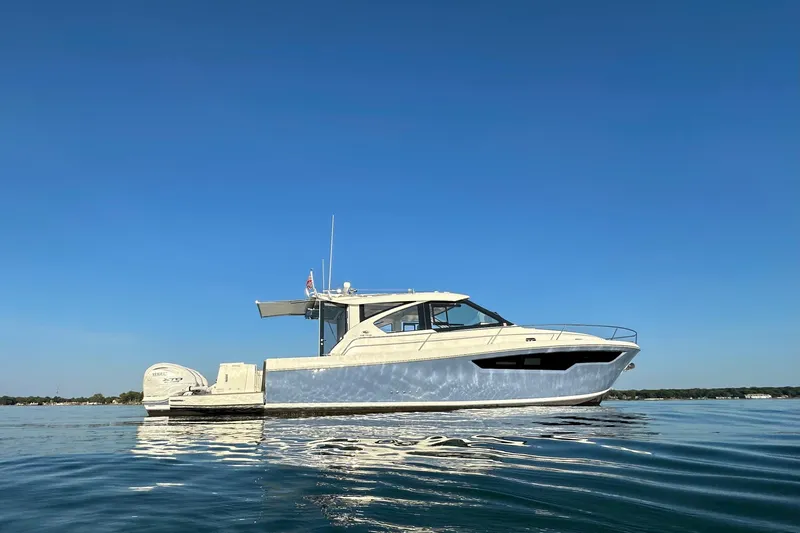  Yacht Photos Pics 2024 Pursuit OS 445 Offshore boat on calm water under clear blue sky.