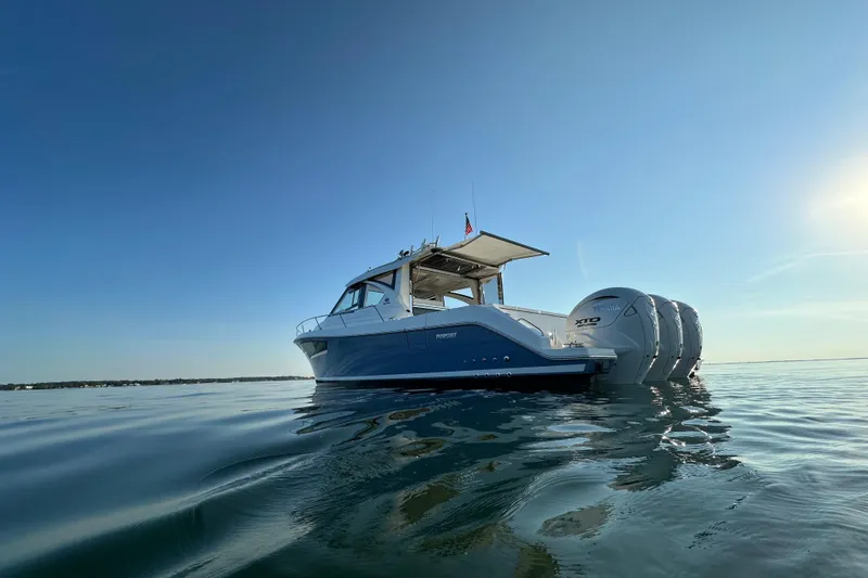  Yacht Photos Pics 2024 Pursuit OS 445 Offshore boat on calm water under clear blue sky.