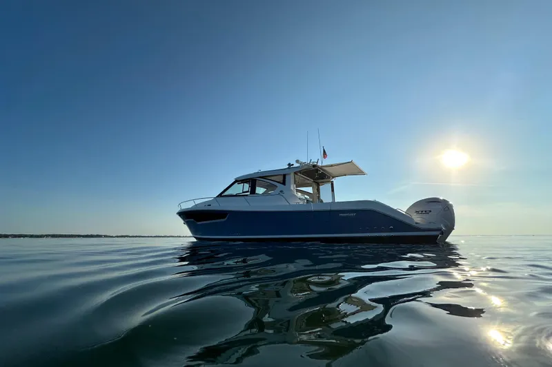  Yacht Photos Pics 2024 Pursuit OS 445 Offshore boat on calm water under a clear sky.