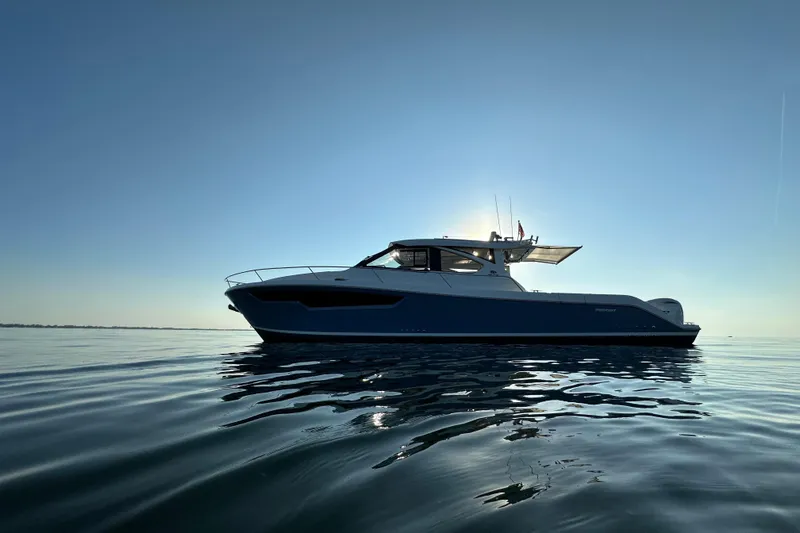  Yacht Photos Pics 2024 Pursuit OS 445 Offshore boat on calm water at sunset.