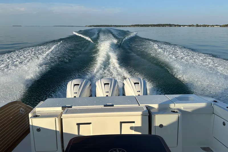  Yacht Photos Pics 2024 Pursuit OS 445 Offshore boat cruising on calm water, leaving a wake behind.