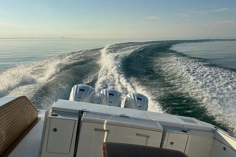  Yacht Photos Pics 2024 Pursuit OS 445 Offshore boat cruising on calm water, leaving a wake trail.