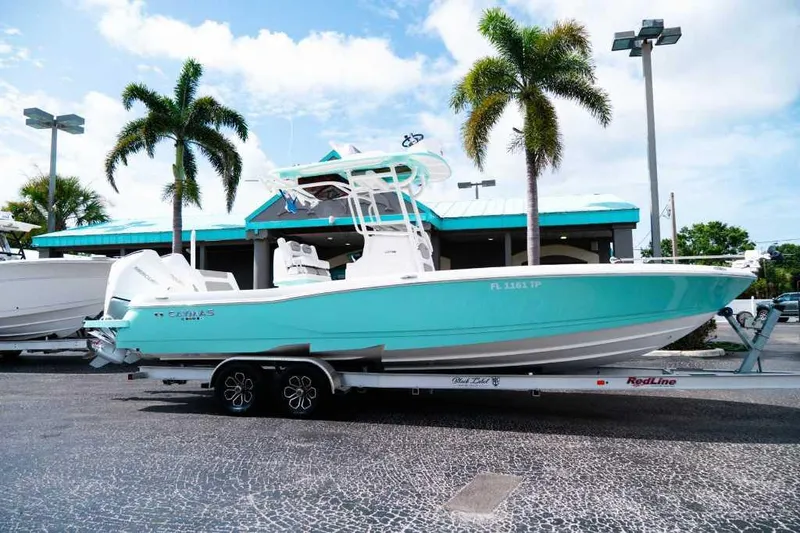 Black Label Marine Yacht Photos Pics 2024 Caymas 281 HB boat on trailer, parked near palm trees and a turquoise building.