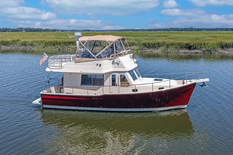 Coastal Fogg Yacht Photos Pics 2006 Mainship 34 Trawler on calm water, featuring a red hull and beige canopy.