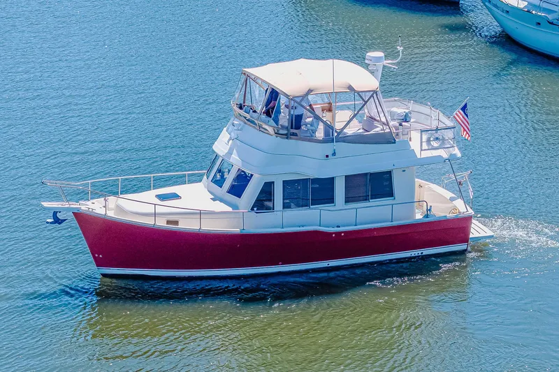 Coastal Fogg Yacht Photos Pics 2006 Mainship 34 Trawler cruising on calm blue waters, featuring a red hull and flybridge.